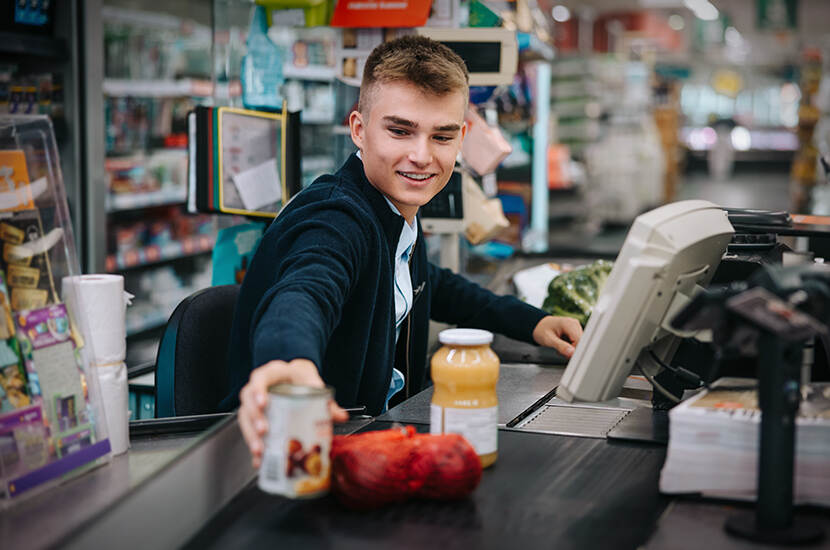 Jongen werkt achter de kassa in een supermarkt en scant artikelen